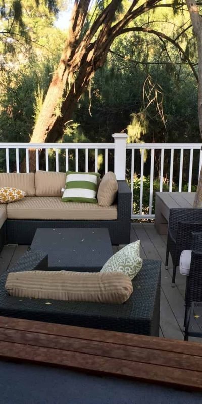 Spacious outdoor deck with sectional sofa and chairs overlooking trees.
