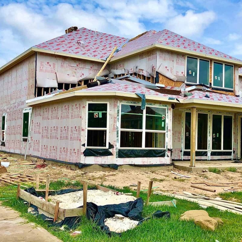 Under construction house with scaffolding and building materials in yard.