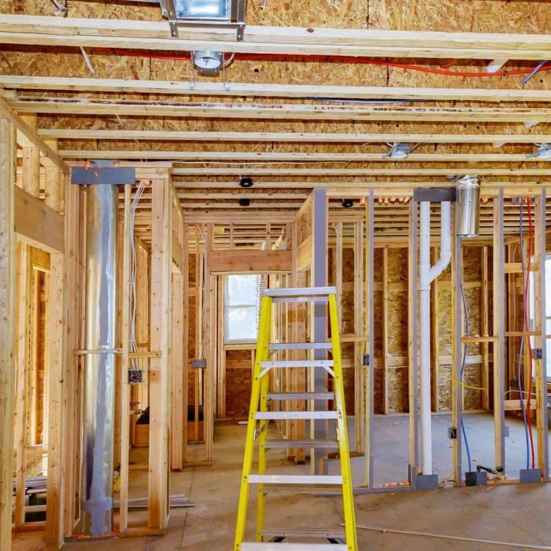 Construction site with wooden framing and metal ductwork in progress.
