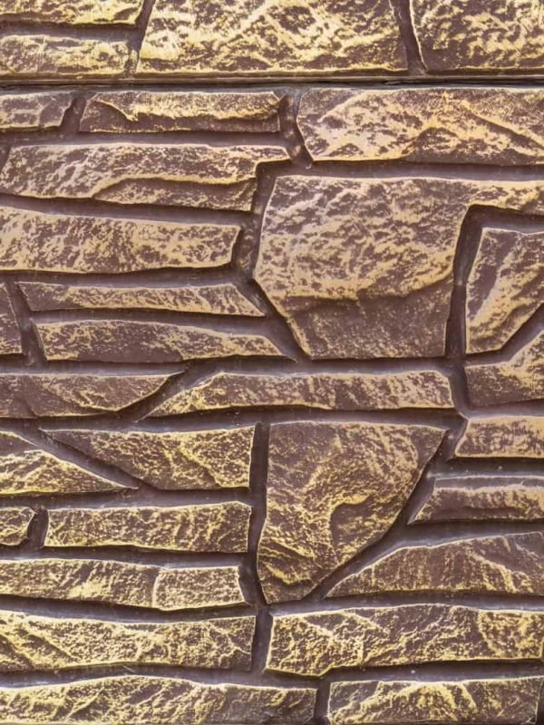 Close-up of textured stone wall with green ivy on the side.